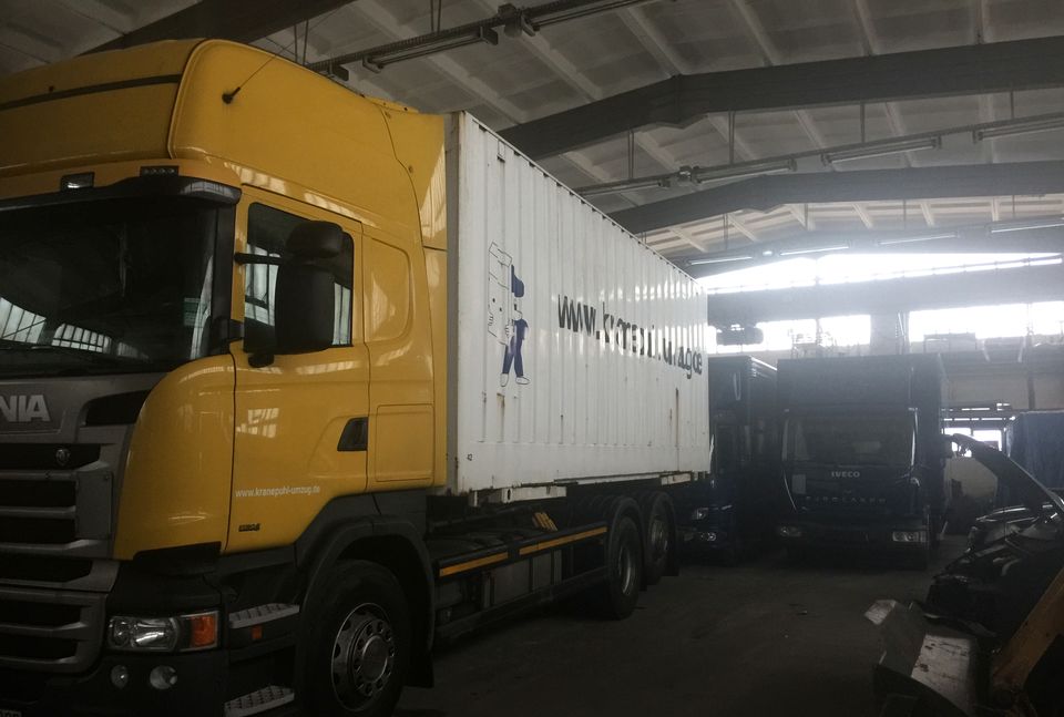 Gelbe Scania-Zugmaschine mit Wechselcontainer in der LKW-Werkstatt von Kranepuhl
