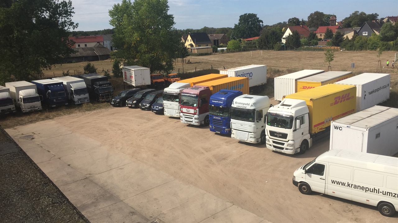 Fuhrpark von Kranepuhl auf dem Betriebsgelände: Umzugs-LKW, Wechselcontainer und Transporter in Reihe