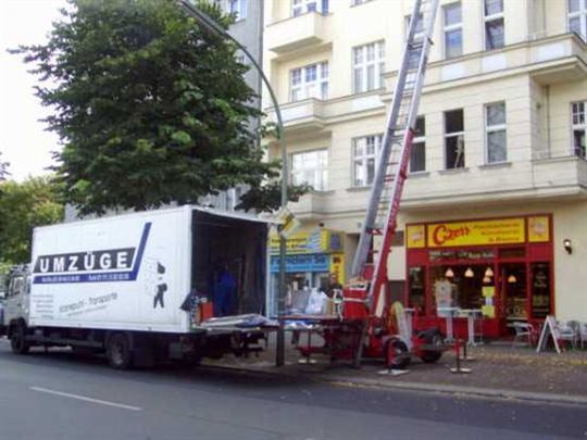 Umzugslift mit beladener Plattform vor einem Wohnhaus